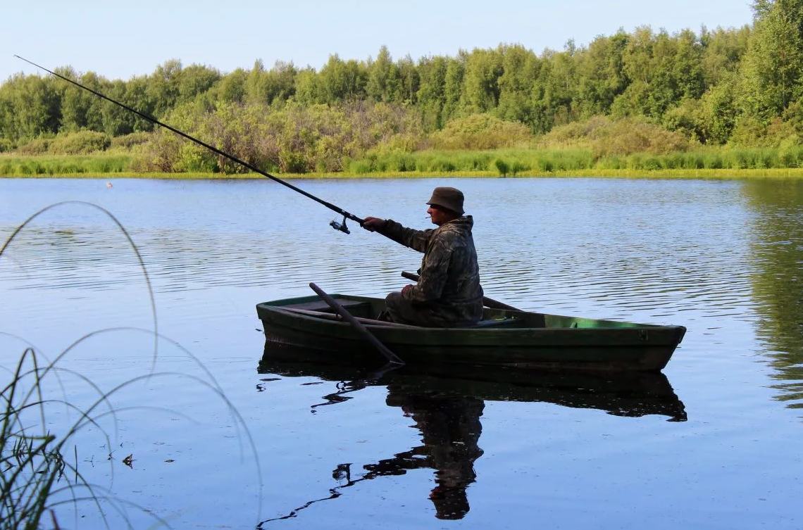 Любительский лов рыбы. Лодка для рыбалки. Рыбак на озере. Рыбак в лодке. Рыбак в лодке на озере.